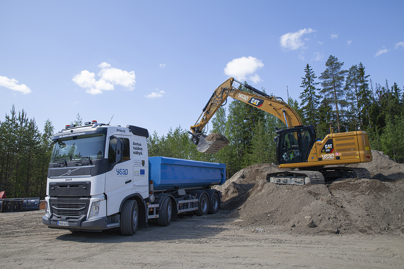 Rakennusalan perustutkinto, maarakennuskoneenkuljettaja opiskelijat työssään Volvo kuorma-auton ja kaivinkoneen kanssa maarakennustyömaalla.