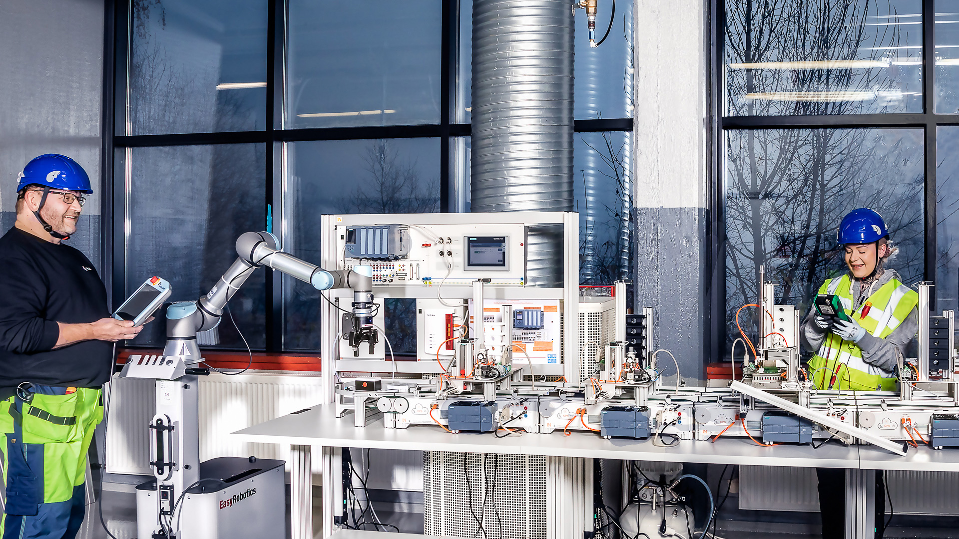 Kaksi sähkö- ja automaatioalan ammattitutkinto -opiskelijaa eli sähköasentajaa ohjaavat minilaborotoriolaitetta Ylä-Savon ammattiopiston oppimisympäristössä.