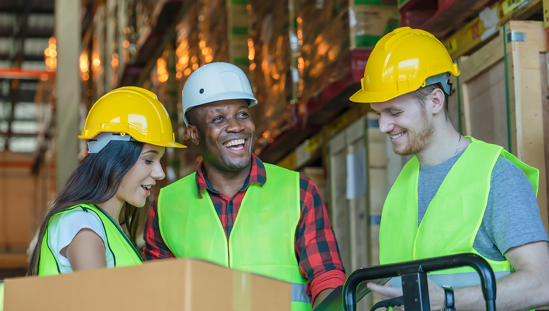 Monikulttuurisen työyhteisön perehdyttäminen ja johtamisen koulutus. Kuvassa työntekijät hymyilevät varastorakennuksessa kun työt sujuvat.