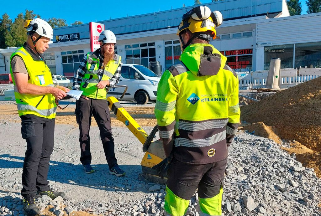 Kolme henkilöä seisoo kadunrakennustyömaalla.