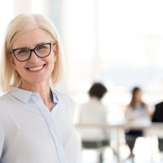 Työhyvinvointikorttikoulutus edistää työyhteisöä. Kuvassa nainen etualalla ja tiimi taustalla.